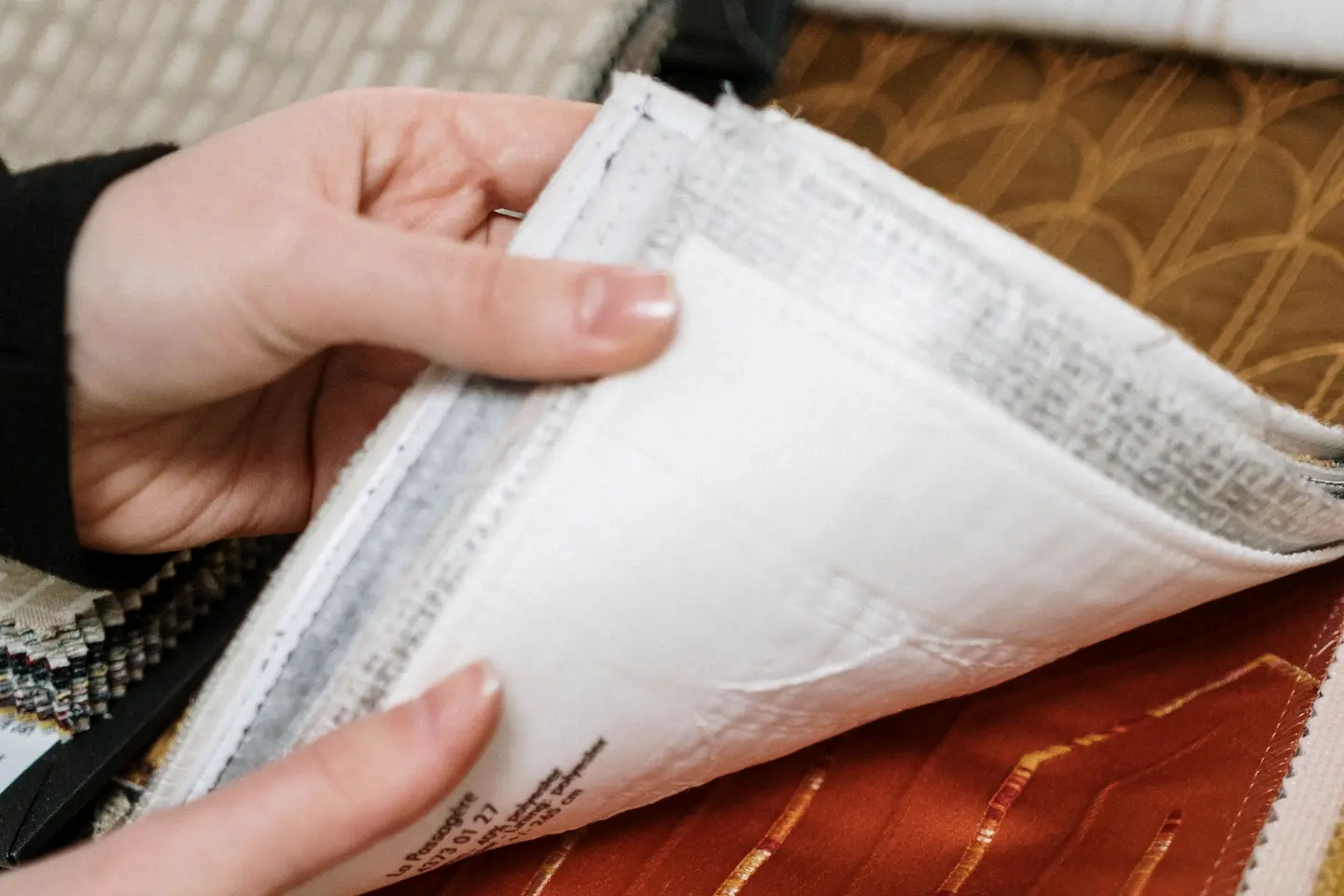 Hands turning the pages of a fabric sample book