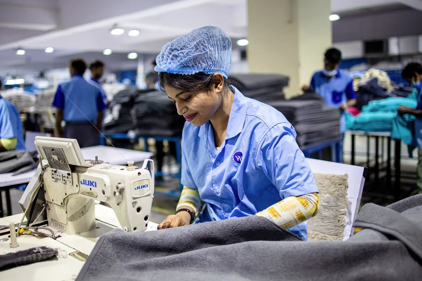 A worker at an industrial sewing machine on a factory floor
