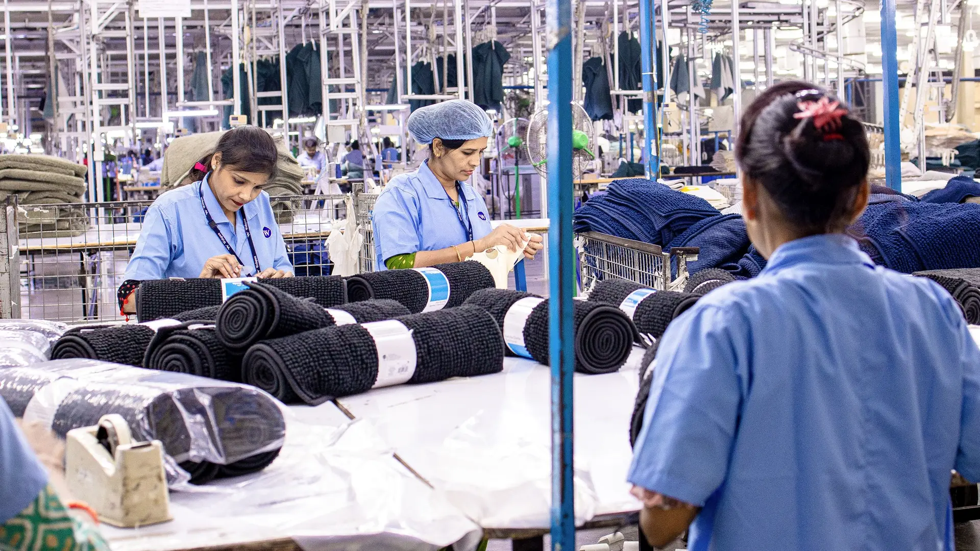 Workers at sewing machines on a busy factory floor